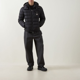 Model wearing Moncler black quilted down jacket with hood, styled with dark trousers and black chunky-sole shoes