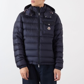 Model wearing Moncler dark blue quilted down jacket with detachable hood, chest pocket, and logo badge detail