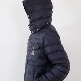 Model wearing Moncler dark blue quilted down puffer jacket with hood up, chest flap pocket and logo badge detail
