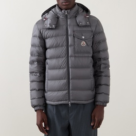 Model wearing Moncler grey quilted down jacket with detachable hood, chest pocket, and logo badge detail