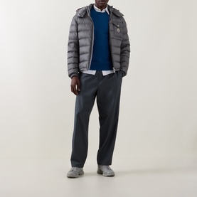 Model wearing Moncler grey quilted down jacket with hood, styled with blue knit, white shirt, and navy trousers