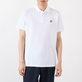 Model wearing Moncler white cotton polo shirt with logo badge on chest, styled with navy trousers