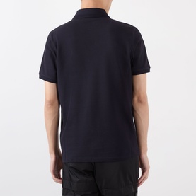 Model wearing Moncler blue cotton polo shirt, rear view, with black trousers