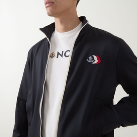 Model wearing Moncler dark blue zip-through sweatshirt with logo badge, styled with a white Moncler logo T-shirt underneath.