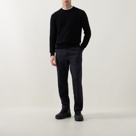 Model wearing Moncler dark blue sweatpants, styled with a black crew-neck sweater and black chunky-sole trainers.