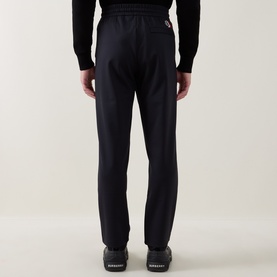 Model wearing Moncler dark blue sweatpants, rear view, styled with black knit top and black trainers.