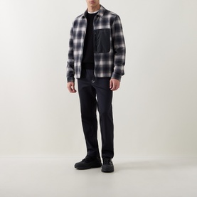 Model wearing Moncler dark blue sweatpants, styled with a grey check overshirt, black top, and black trainers.