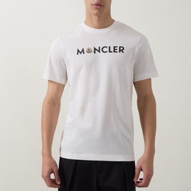 Model wearing Moncler natural white cotton T-shirt with bold logo lettering and signature badge graphic to chest.