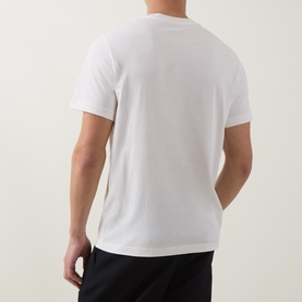 Model wearing Moncler natural white cotton T-shirt, back view, styled with black trousers.