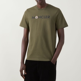 Model wearing Moncler dark green cotton T-shirt with chest logo lettering, styled with black trousers.