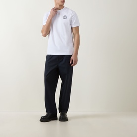 Model wearing Moncler white cotton T-shirt with chest logo, styled with navy tailored trousers and black loafers