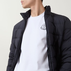 Model wearing Moncler white cotton T-shirt with chest logo patch, styled with a black quilted zip-up jacket.