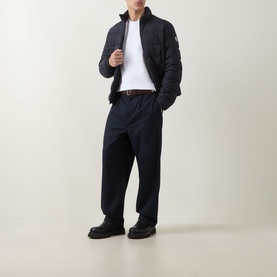Model wearing Moncler white cotton T-shirt, styled with navy quilted jacket, navy trousers, and black leather shoes.