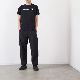 Model wearing Moncler Felt Logo Graphic T-Shirt in navy with black cargo trousers and black trainers.