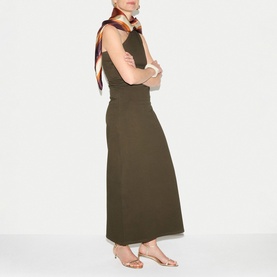Model wearing Jigsaw khaki sleeveless maxi dress with open back, styled with a striped scarf and strappy sandals.