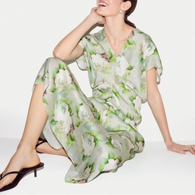 Model wearing Jigsaw green floral midi dress with short flutter sleeves and V-neckline, styled with black heeled mules