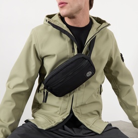Model carrying Stone Island Logo Badge Belt Bag in black, worn crossbody, styled with a sage green hooded jacket.