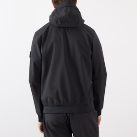 Model wearing Stone Island Soft Shell-R-e.dye&reg; Wind Resistant Jacket in black, rear view showing raglan sleeves, hood and sleeve badge detail.