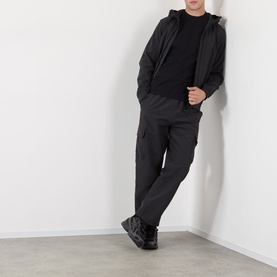 Model wearing Stone Island Soft Shell-R-e.dye&reg; Wind Resistant Jacket in black, styled with matching black cargo trousers and black trainers.