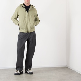 Model wearing Stone Island Softshell-R_e.dye&reg; Wind Resistant Jacket in Laurel Green with dark trousers and trainers.