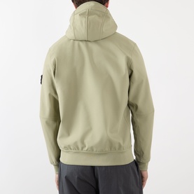 Model wearing Stone Island Softshell-R_e.dye&reg; Wind Resistant Jacket in laurel green, rear view showing hood, raglan sleeves and logo patch on left