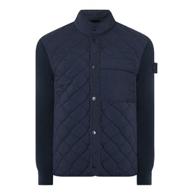 Stone Island blue quilted casual jacket with knit sleeves, chest pocket, snap-button fastening, and signature arm badge patch.