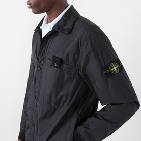 Model wearing Stone Island black nylon casual jacket with chest snap pocket and signature compass badge on sleeve, styled with white shirt