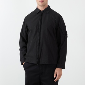 Model wearing Stone Island black cotton casual shirt jacket with zip front, spread collar, and signature arm badge detail.