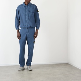 Model wearing Stone Island Blu Ardesia cotton casual shirt with matching trousers and grey trainers.