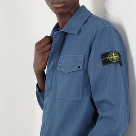 Model wearing Stone Island casual shirt in Blu Ardesia, featuring chest pockets, spread collar and signature compass badge on sleeve.