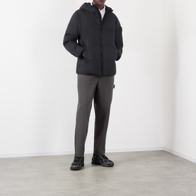 Model wearing Stone Island black casual jacket with hood, styled with grey tapered trousers and black boots
