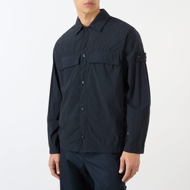 Model wearing Stone Island blue polyamide casual shirt with chest pockets, snap button fastening, and signature arm badge