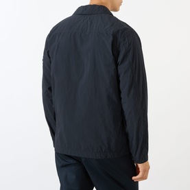 Model wearing Stone Island blue polyamide casual shirt jacket, rear view, showing collar and relaxed fit, styled with navy trousers