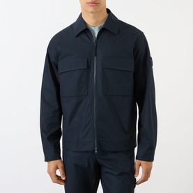 Model wearing Stone Island Tonal Logo Badge Zip Overshirt in blue, with point collar, chest flap pockets and two-way zip fastening