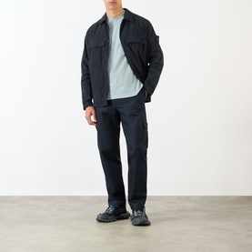 Model wearing Stone Island Blue Tonal Logo Badge Zip Overshirt with matching navy cargo trousers and dark chunky-sole trainers.