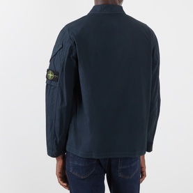 Model wearing Stone Island navy blue cotton casual shirt, rear view, showing signature compass badge patch on left sleeve.