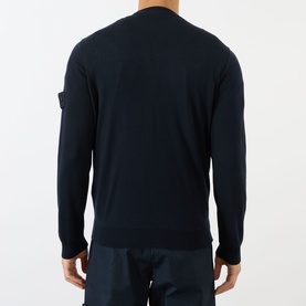 Model wearing Stone Island blue virgin wool crew neck jumper, rear view, featuring signature arm badge detail.