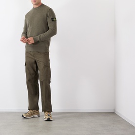Model wearing Stone Island Verde Militare Melange wool crew neck jumper with olive cargo trousers and tan trainers.