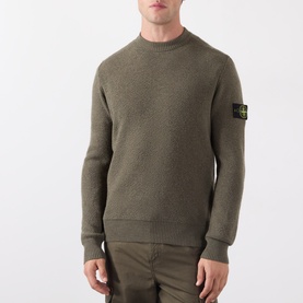 Model wearing Stone Island Verde Militare Melange wool crew neck knit with signature sleeve badge, styled with olive trousers.
