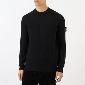 Model wearing black Stone Island crew neck knit sweatshirt with signature compass badge patch on left sleeve