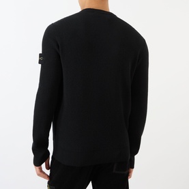 Model wearing black crew neck knit jumper with Stone Island badge patch on left sleeve, back view