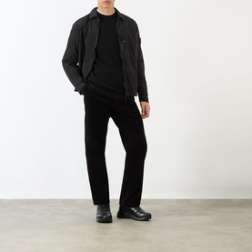 Model wearing black zip-up jacket, black crew-neck top, black trousers and black lace-up shoes, full-length front view