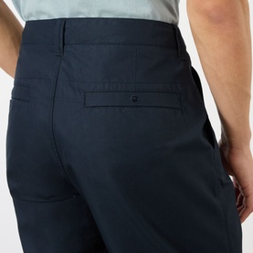 Model wearing Stone Island blue cotton chino trousers, rear view showing back pocket detail and clean tailored finish.