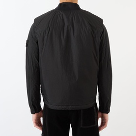 Model wearing Stone Island Logo Badge Gilet in black, shown from behind, with bomber collar and logo badge on sleeve.