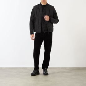 Model wearing Stone Island Logo Badge Gilet in black, styled with black trousers and black boots.