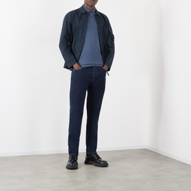 Model wearing Stone Island Blue Rinse jeans with a navy jacket, blue polo shirt and black leather shoes.