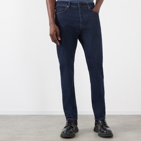 Model wearing Stone Island Blue Rinse slim-fit jeans, styled with black leather lace-up shoes, cropped at waist.
