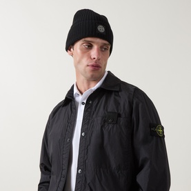 Model with Stone Island black ribbed wool beanie hat, styled with matching black nylon overshirt jacket with compass rose badge patch.