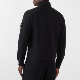Model wearing Stone Island black cotton zip-neck sweatshirt, rear view, with badge logo on left sleeve, styled with matching black joggers.