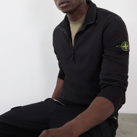 Model wearing Stone Island black half-zip polo with compass badge patch on sleeve, styled with black trousers